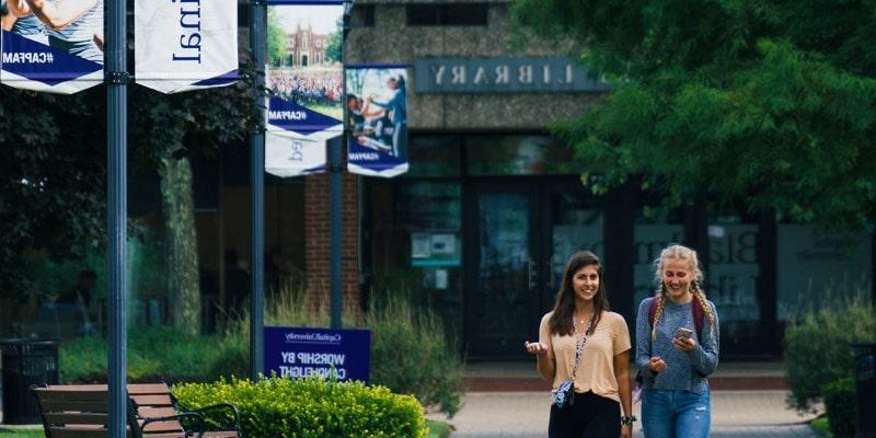 两个女大学生一起走在万博图书馆前的小路上